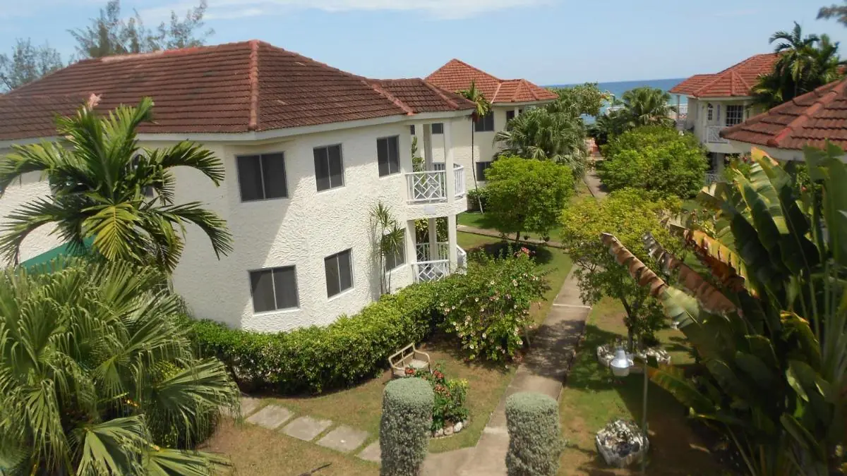 De gebouwen van Pipers Cove Resort tussen tuinen en palmbomen