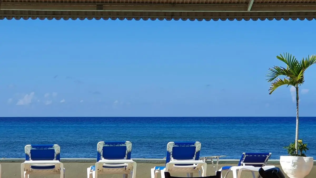 Blauwe ligbedden en het zwembad van Pipers Cove Resort, aan de Caribische Zee